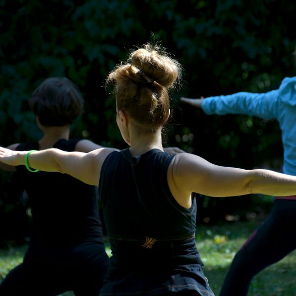 Child balancing carefully in a tree yoga pose in a park.